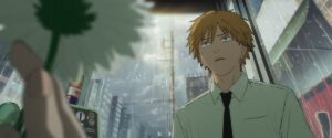 Chainsaw Man Reze Arc Movie Hits $13.5 Million Box Office in Just 6 Days 1 A person with messy blond hair, dressed in a light green collared shirt and black tie, stands at a bus stop on a rainy day. In the foreground, a hand holds a white daisy. Raindrops streak down the glass behind, and a cityscape with buildings and power lines is visible outside.