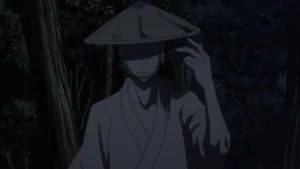8 Anime That Were Underrated in Their Time 2 An anime character with white hair wearing a conical hat and a light-colored kimono stands in a dark forest at night, with his face mostly obscured by shadow.