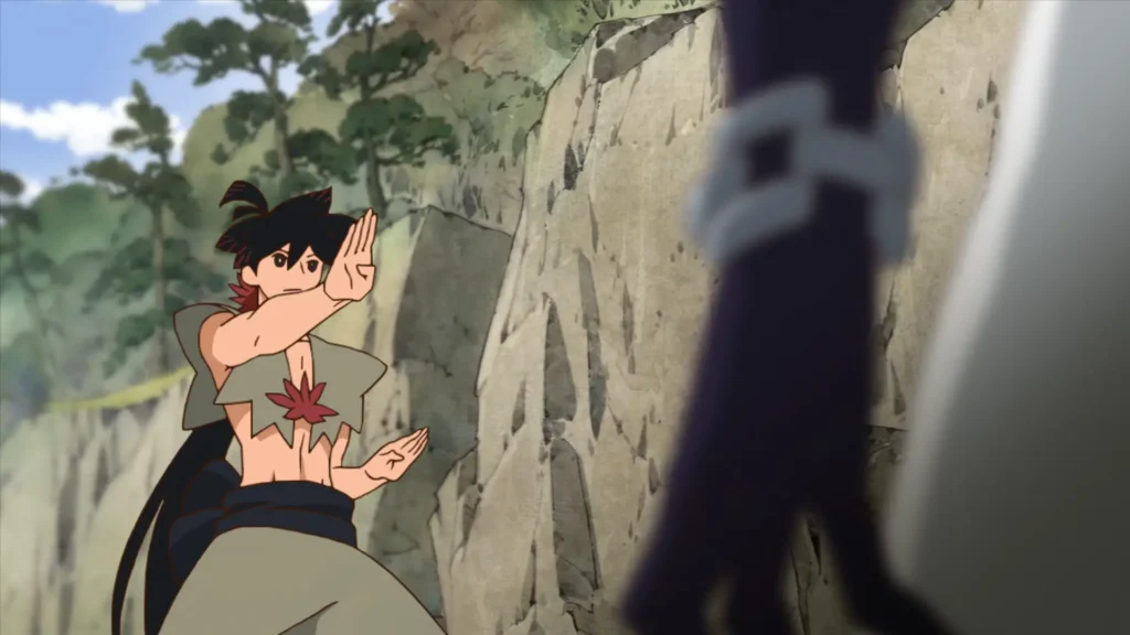 Anime scene in a rocky mountain pass: a lean, black‑haired youth with a long ponytail and tattered cropped top (decorated with a red maple leaf emblem) assumes a twin open‑palm defensive martial arts stance. Forested cliffs and a rope bridge blur in the background. A tall, dark‑clad opponent’s leg and hip cross the extreme right foreground out of focus, implying imminent close‑quarters confrontation.